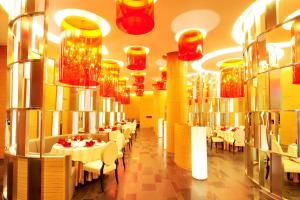 uma sala de jantar com mesas brancas e lustres vermelhos em Aloft Zhengzhou Shangjie em Zhengzhou