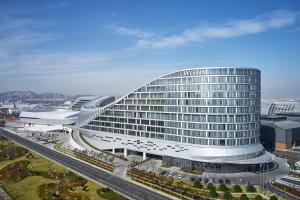 un gran edificio de cristal con una autopista delante de él en The Westin Qingdao West Coast en Huangdao