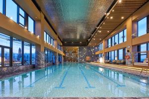 a large swimming pool in a building with windows at The Westin Qingdao West Coast in Huangdao