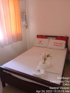 WJV INN MARIBAG0 في Maribago: غرفة نوم مع سرير مع إناء من الزهور عليه