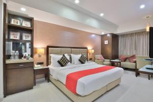 a bedroom with a large bed and a living room at Krios Hotel in Ahmedabad