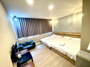 um pequeno quarto com uma cama e um sofá em 逢甲旅人Inn em Taichung