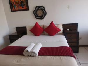 Schlafzimmer mit einem Bett mit roten und weißen Kissen in der Unterkunft Rose Guest House in Pretoria