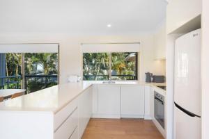 a white kitchen with white cabinets and windows at Bombora in Lennox Head