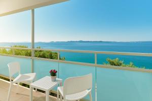 a balcony with chairs and a table with a view of the ocean at Hotel Pinija in Petrcane