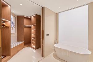 ein Badezimmer mit einer großen Badewanne und einem begehbaren Kleiderschrank in der Unterkunft Ajman Hotel by Blazon Hotels in Ajman 