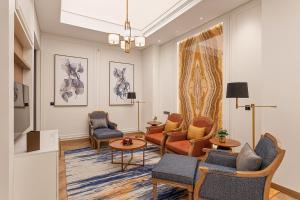 Ajman Hotel by Blazon Hotels في عجمان: غرفة معيشة مع كراسي وأريكة وطاولات