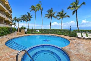 a large swimming pool with palm trees in the background at Paki Maui 424 in Kahana