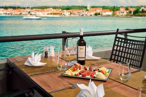 a table with a plate of food and a bottle of wine at Hotel Pinija in Petrcane