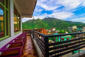 uma varanda com bancos e vista para as montanhas em Manzil Hostel em Rishikesh