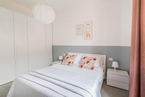 Dormitorio blanco con cama con almohadas rojas y blancas en Casa di Lolli, en Milán