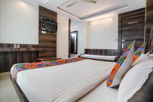 a bedroom with a large white bed with colorful pillows at FabHotel Kingdom Sai in Shirdi