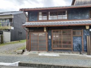 une maison avec une porte en bois et un portail dans l'établissement 古民家クルンズ, à Mino
