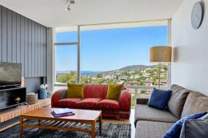 ein Wohnzimmer mit einem Sofa und einem großen Fenster in der Unterkunft Poet s House 6br fabulous character WOW views in Hobart