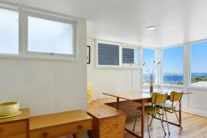 ein Esszimmer mit einem Tisch, Stühlen und Fenstern in der Unterkunft Poet s House 6br fabulous character WOW views in Hobart