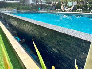 a swimming pool with blue water and people sitting in chairs at 1Bedroom+Sofa bed, Luxury Condo@Nimmana in Chiang Mai