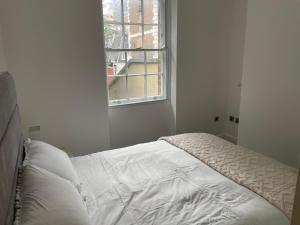 an unmade bed in a white room with a window at London City 1 Bed with Roof Terrace in London