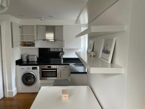 a white kitchen with a stove and a washing machine at London City 1 Bed with Roof Terrace in London