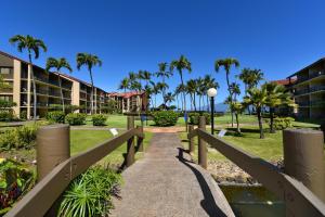 a walkway through a park with palm trees and buildings at Papakea B201 in Kahana