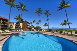 uma piscina no resort com palmeiras em Papakea B201 em Kahana