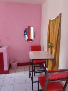 ein Esszimmer mit rosa Wänden sowie einem Tisch und Stühlen in der Unterkunft WJV INN Cordova in Cebu City