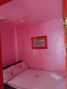 a pink room with a bed and a window at WJV INN Cordova in Cebu City
