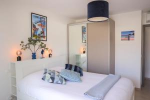 una camera da letto con un letto bianco con cuscini blu di Appartement La Balagne , Bord de mer, Grande Terrasse, Sant'Ambroggio a Lumio