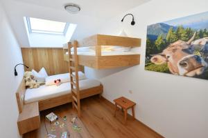 Habitación pequeña con literas y una pintura de una vaca. en Ausserharmerhof App Bergdiamant, en Santa Maddalena in Casies 4 fotos más