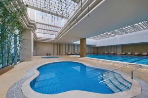 uma piscina num edifício com uma grande piscina em The Westin Tianjin em Tianjin