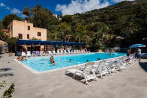 a large swimming pool with chairs and people in it at Villaggio La Marée in Pisciotta