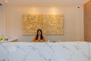 a woman sitting at a counter in a room with a painting at The Baliem Hotel in Jimbaran
