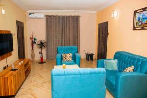 a living room with blue chairs and a flat screen tv at Cogent Apartments in Uyo