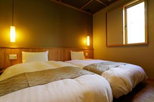 two beds in a bedroom with a window at Yukemuri no Yado Inazumi Onsen in Yuzawa