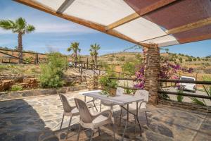 a patio with a table and chairs and palm trees at Paraje la Suerte Apartamento Dalia in Adra