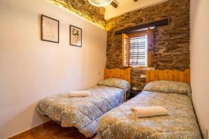 a bedroom with two beds and a stone wall at Paraje la Suerte Apartamento Dalia in Adra +14 photos
