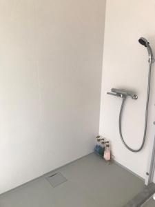 łazienka z prysznicem w białej ścianie w obiekcie glampark resort Akuna beach w mieście Henza