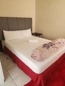 ein großes weißes Bett mit einer roten Decke drauf in der Unterkunft HUNTERS NEST GUEST HOUSE MAFIKENG in Mahikeng