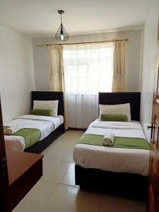 two beds in a room with a window at Furnished Homes Nakuru with pool & GYM in Nakuru