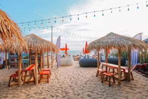 uma praia com mesas, cadeiras e guarda-sóis em Bayphere Hotel Pattaya em Praia de Jomtien