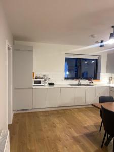 メイヌースにあるPrivate room in a new shared apartmentの白いキャビネット、窓、テーブル付きのキッチンが備わります。