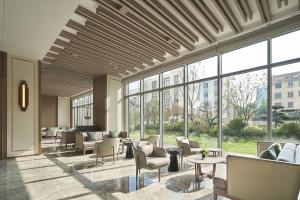 a lobby with chairs and tables and large windows at Four Points by Sheraton Suzhou, Wuzhong in Suzhou