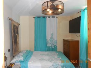 a bedroom with a bed with blue curtains and a chandelier at Gustave Vacation House in Port-au-Prince