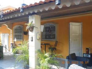 ein orangefarbenes Haus mit einer Veranda mit einem Tisch und Stühlen in der Unterkunft Gustave Vacation House in Port-au-Prince