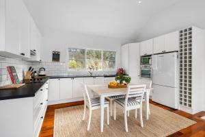 Una cocina con gabinetes blancos y una mesa y sillas. en Mornington Peninsula Hamptons Inspired Gem - New listing, en Rye