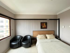 ein Schlafzimmer mit einem Bett und zwei schwarzen Stühlen in der Unterkunft Studio at Grand Setiabudi Apartment in Bandung