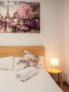 ein Schlafzimmer mit einem weißen Bett und einem Gemälde an der Wand in der Unterkunft Central apartment, Burjasot in Valencia