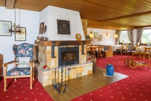 a room with a fireplace and a chair and tables at Gästehaus beim Schneidersepp in Ruhpolding