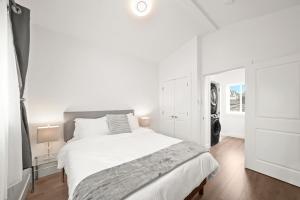 a white bedroom with a large bed and a window at Entire NEW Cozy and Modern 2-storey HOUSE in Vancouver