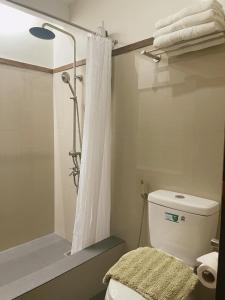 a bathroom with a shower and a toilet with a shower curtain at Soleo Inn in Baguio