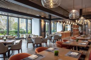 un ristorante con tavoli, sedie e finestre di Courtyard by Marriott Suzhou Mudu a Suzhou